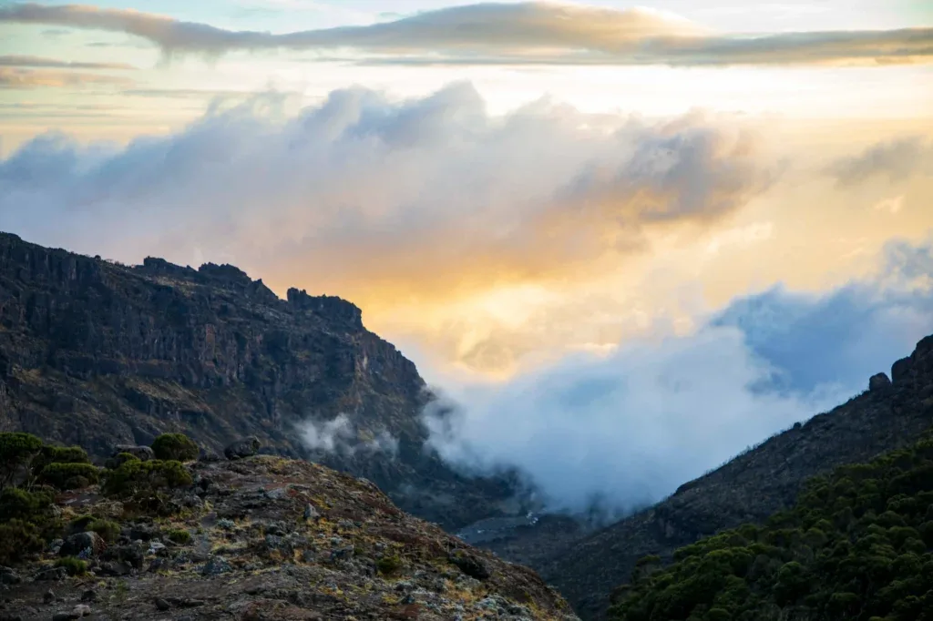 Sunlight breaking through clouds over a mountain valley
