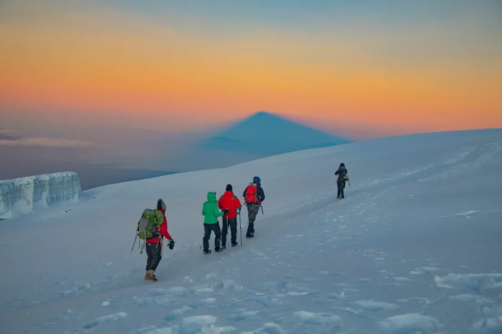 Climbers crossing snowy mountain terrain at dawn